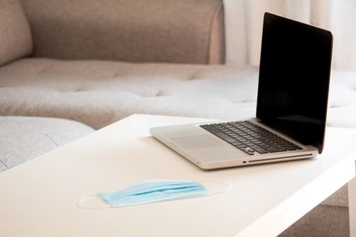 A laptop and protective mask on the table- COVID-19