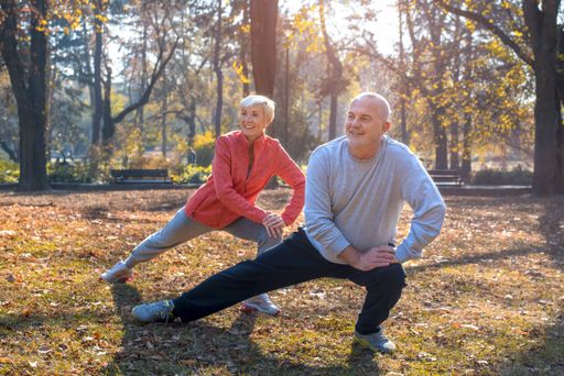 A closeup of smiling Caucasian senior couple exercising in a park on a sunny autumn day
