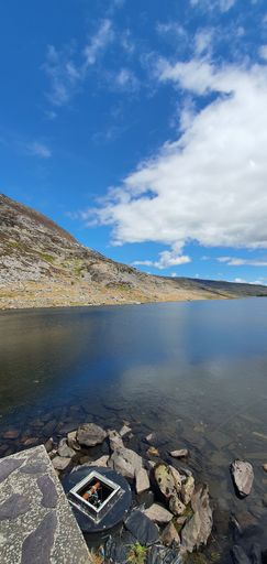 A vertical shot of the cloudy blue sky over the calm lake on a sunny day in spring