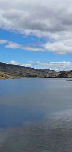 A vertical shot of the cloudy blue sky over the calm lake on a sunny day in spring