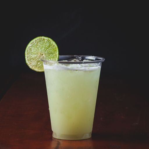 A closeup of a cocktail in a plastic cup with a lime slice