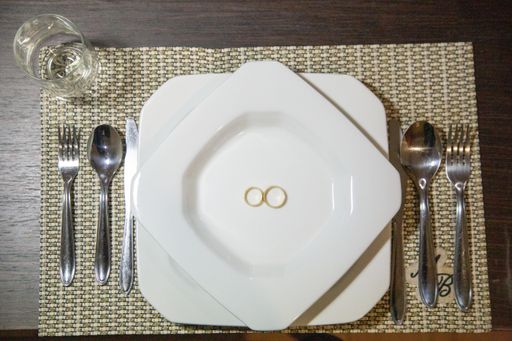 A top view of golden wedding rings on a white plate on a wooden table