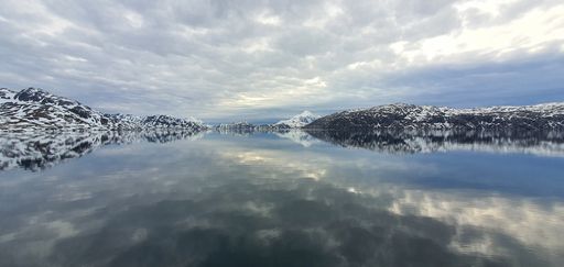 The reflection of clouds on the lake surrounded by snowy mountains