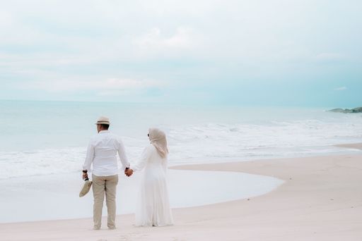 A couple enjoying the beach waves together holding hands and standing on the sandy beach