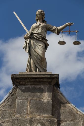 A low angle shot of the statue of justice on a pedestal against cloudy blue sky in Dublin, Ireland