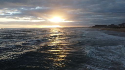 A scenic view of a vast blue ocean in a bright sunset sky background