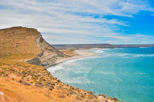 The beautiful and calm ocean surrounded by the cliffs under the cloudy blue sky