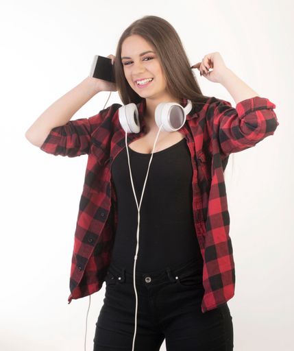 A happy caucasian female with her headphones and smartphone isolated on a white background