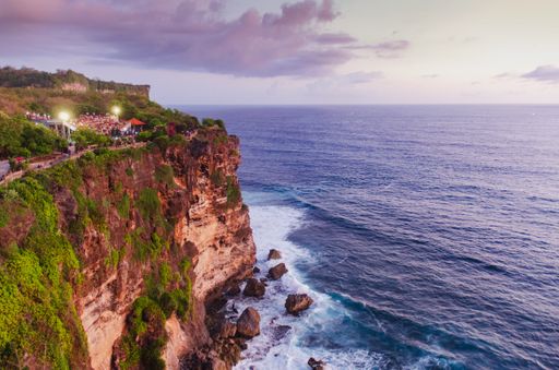 A high angle shot of buildings on a cliff near the sea under a blue cloudy sky
