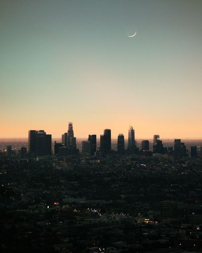 A dramatic vertical high angle shot of the Moon above downtown Los Angeles