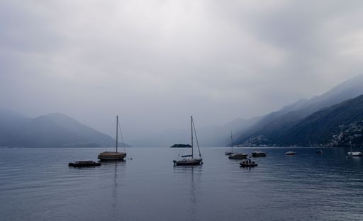 A beautiful view of sailing boats in the middle of the water and the mountains around it