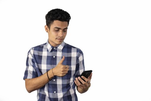 A young Hispanic male doing a thumbs up sign at his phone isolated on a white background