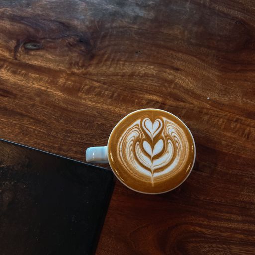 A top view of a latte with heart foam art on a wooden surface