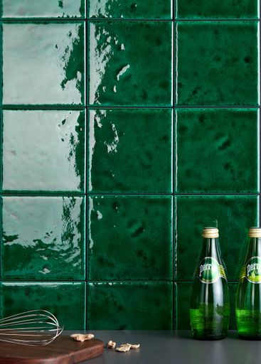 A vertical shot of Perrier bottles against a green tiles wall in the kitchen