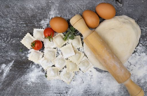 top view rolling pin with tomatoes, dough, eggs, flour and ravioli