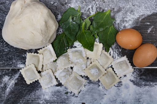 top view dough with spinach eggs, flour and ravioli on wood