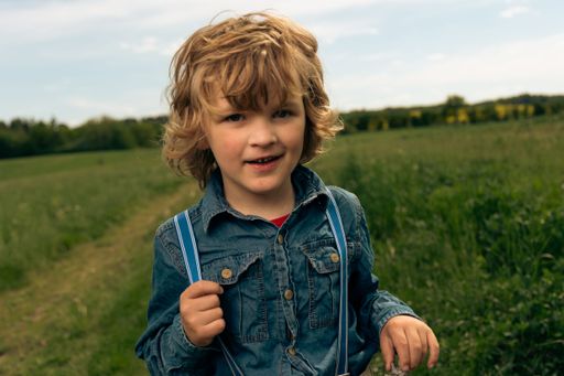 A closeup shot of an autistic Caucasian baby boy with blonde hair playing in a park on a sunny day