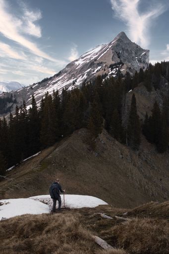 A vertical shot of a brave man hiking in the mountains of Switzerland