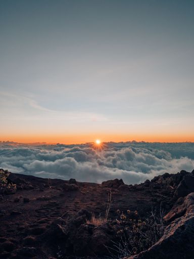 a vertical shot of sunset above the clouds on the mountain in Mau, Hawaii