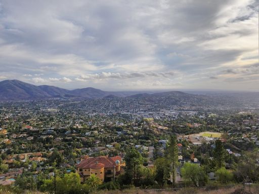 An aerial view of a city in greenery near the hills on a cloudy day