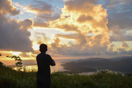 A man enjoying a mesmerizing view of a beautiful seascape at scenic sunset under a cloudy sky