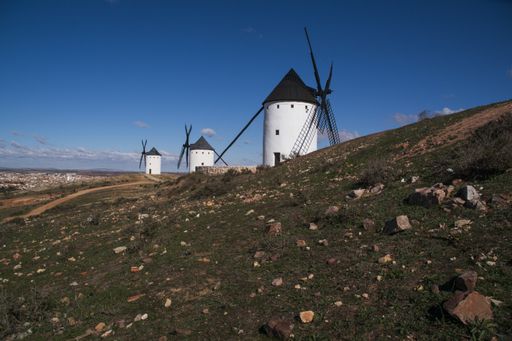 A beautiful shot of white windmills in the field under a blue sky