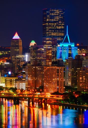 A vertical shot of the skyline of Pittsburgh in PA with lights at night