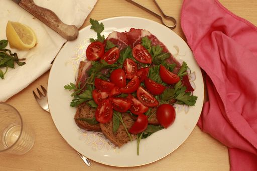 An overhead shot of salad served in a white plate on a wooden table