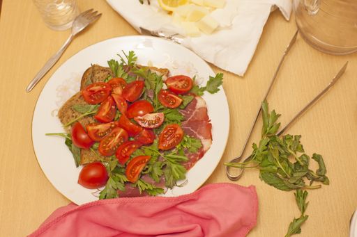 An overhead shot of salad served in a white plate on a wooden table