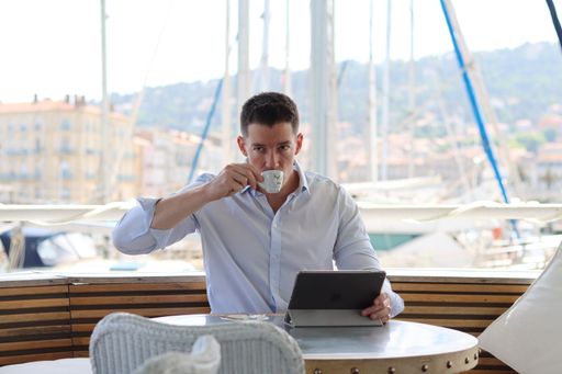 A young man working on his tablet with his coffee and his smartwatch on a terrace of a restaurant