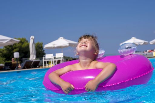 A shallow focus shot of a cute young female in inflatable ring swimming in a pool