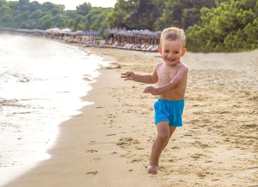 A shallow focus shot of a young male running on a sandy beach