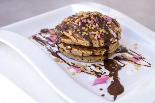 The pancakes with chocolate and pink crème and nuts served on a white plate