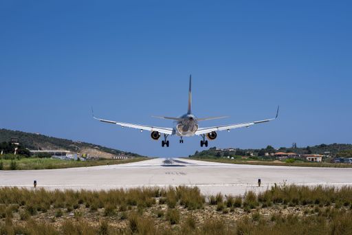 A closeup shot of a plane landing in a small airport with houses and forests on the background
