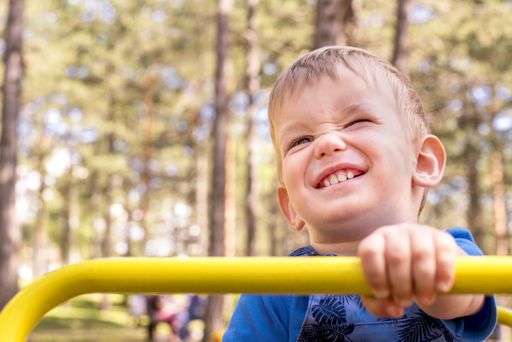 A shallow focus shot of a smiling kid having fun in the playground