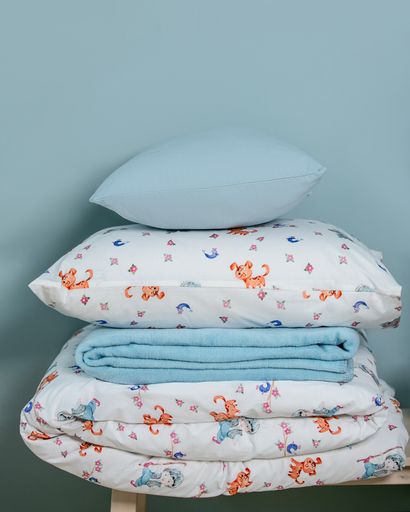 A vertical shot of a child bed linen set and pillows on a blue background