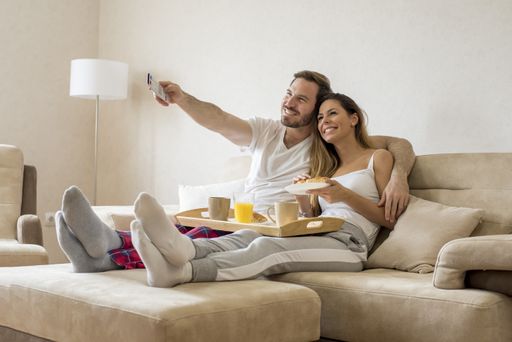 A beautiful couple sitting on a beige sofa with a breakfast