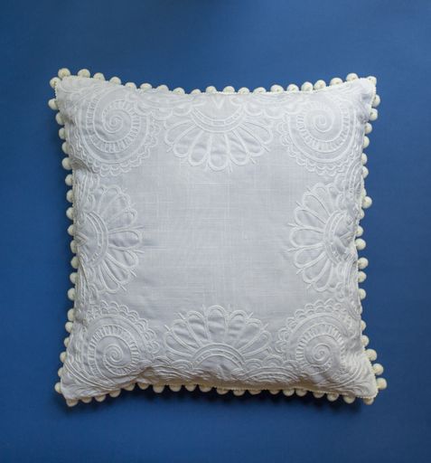 A white decorative pillow on a blue background