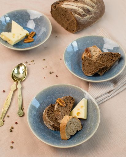 A vertical closeup shot of a breakfast table with bread, cheese and snacks