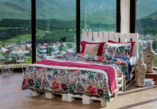A king-size bed with floral decorations on bed linens and the beautiful view of the village in the background