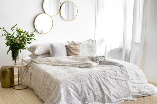 A bedroom with a white patterned linen bed and decorations