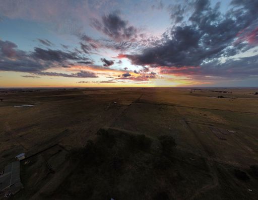 A drone panoramic shot of Sunset with cloudy sky over a big Farm