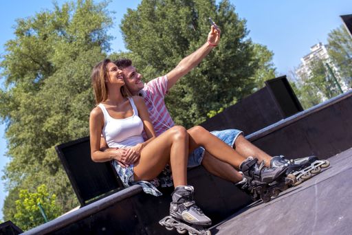 A low angle shot of a couple with roller skates sitting in the park under the sunlight