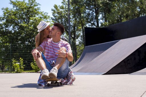 A beautiful couple sitting at a skatepark under the sunlight