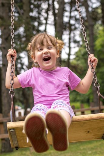 A vertical shallow focus shot of a young female swinging on a swing in playground