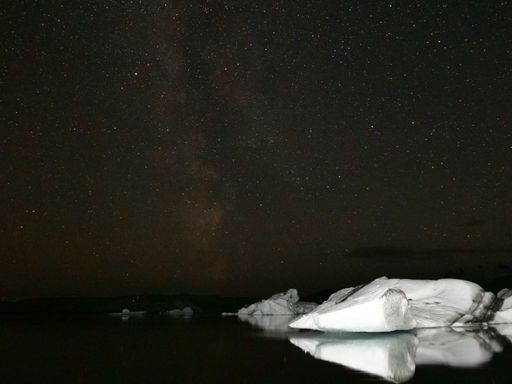 A scenic view of icebergs under a dark starry night in Iceland