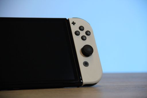 A closeup of a Nintendo Switch OLED Gaming Handheld on a wooden table