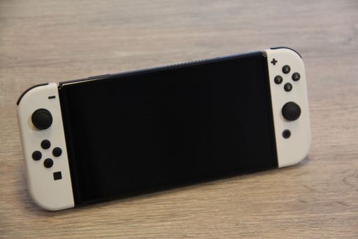 A closeup of a Nintendo Switch OLED Gaming Handheld on a wooden table
