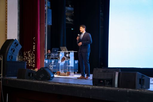 A man in suit standing on stage during medical event in Alexandria opera house