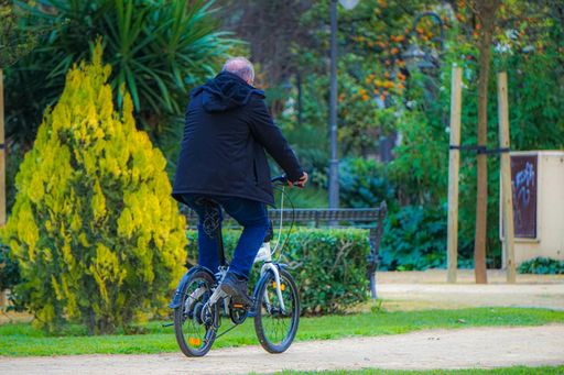 A closeup shot of a male riding a bicycle outdoors surrounded by trees and bushes